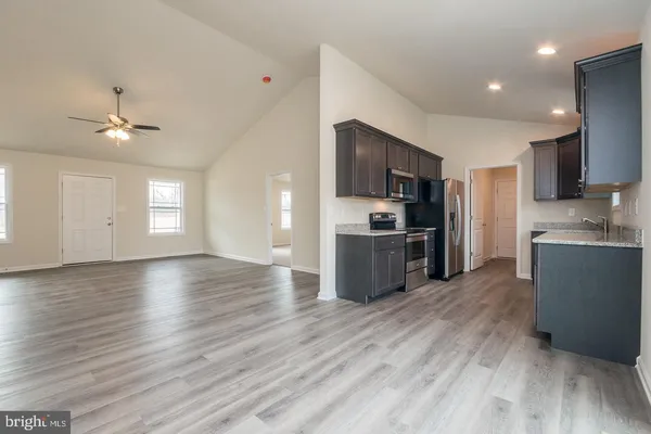 a kitchen with stainless steel appliances granite countertop a refrigerator a stove top oven a sink dishwasher and wooden floor