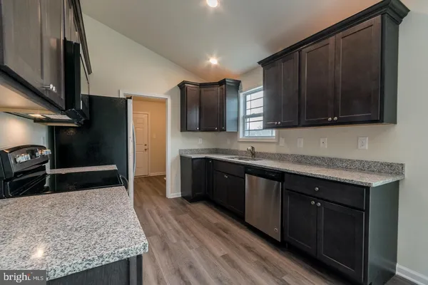 a kitchen with stainless steel appliances granite countertop wooden cabinets a refrigerator and a sink
