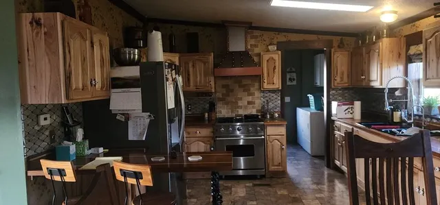 a kitchen with stainless steel appliances kitchen island granite countertop a refrigerator and a stove