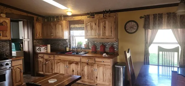 a kitchen with stainless steel appliances granite countertop a refrigerator a stove top oven a clock and a window