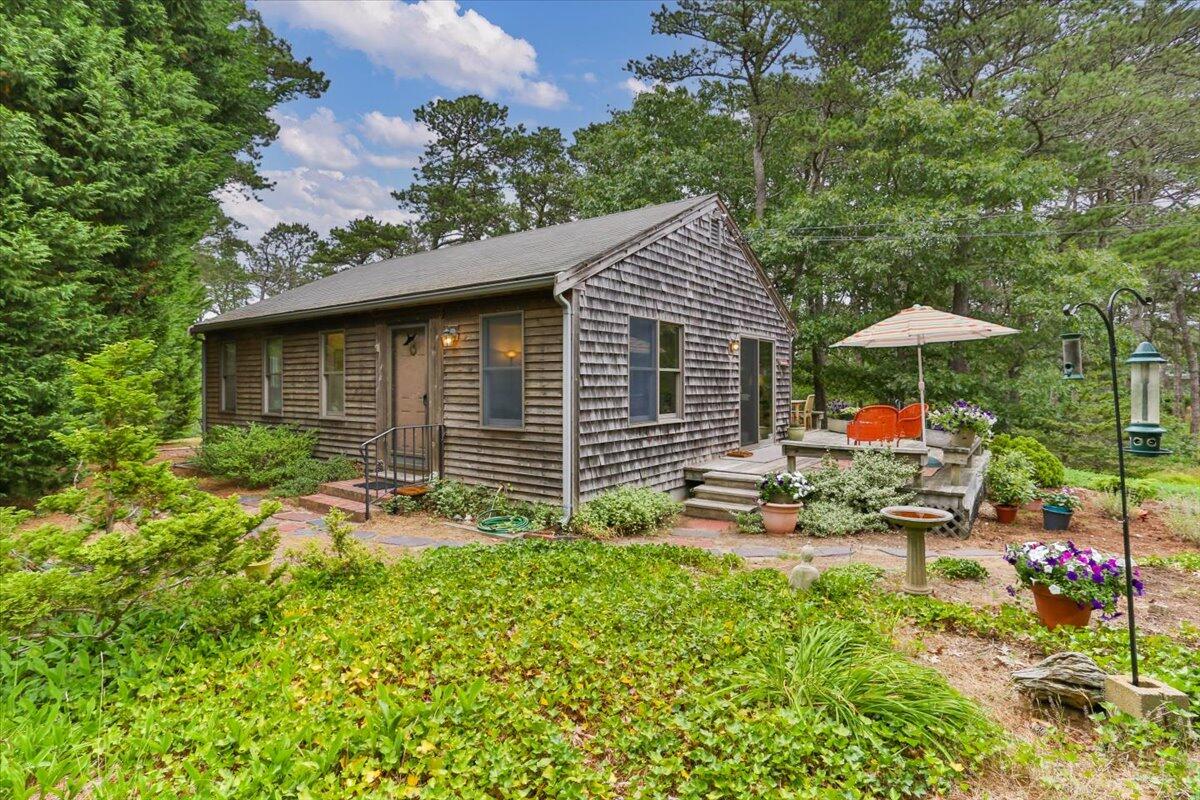 a backyard of a house with table and chairs under an umbrella