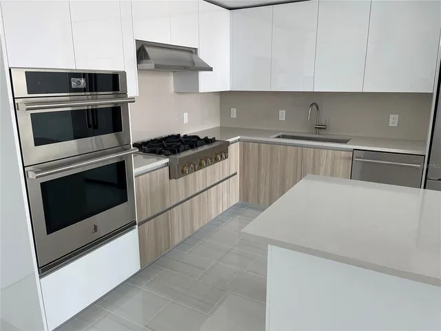 a kitchen with stainless steel appliances a stove microwave and sink