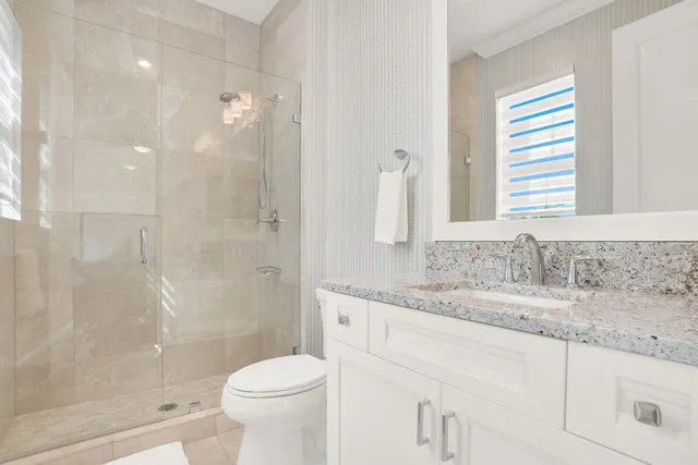 a bathroom with a granite countertop sink a toilet and a mirror