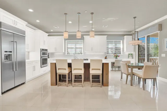 a dining area with stainless steel appliances kitchen island granite countertop a dining table chairs and view living room