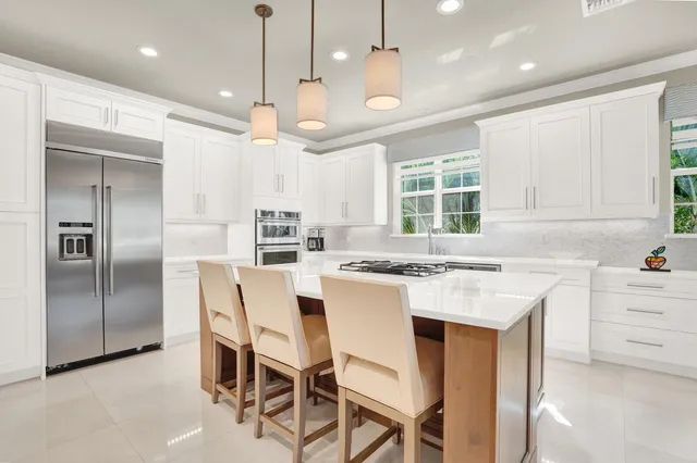 a kitchen with kitchen island a large counter top space stainless steel appliances a window and cabinets