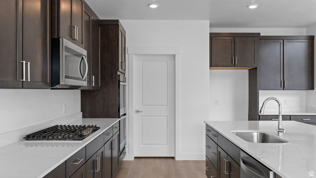 4170 North 560th West, Unit 6 Tooele, UT 84074 - Photo 4 of 20 Contemporary kitchen featuring dark wood cabinetry, white countertops, stainless steel appliances, a gas cooktop, and a kitchen island with an undermount sink