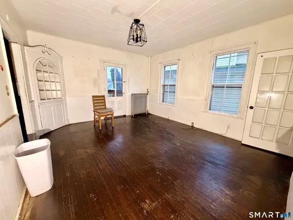 a view of an empty room with glass door and wooden floor