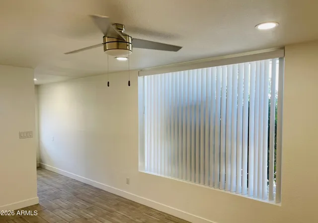 an empty room with wooden floor cabinet and windows