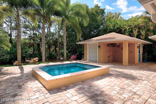 a view of a white house with a large pool and large tree