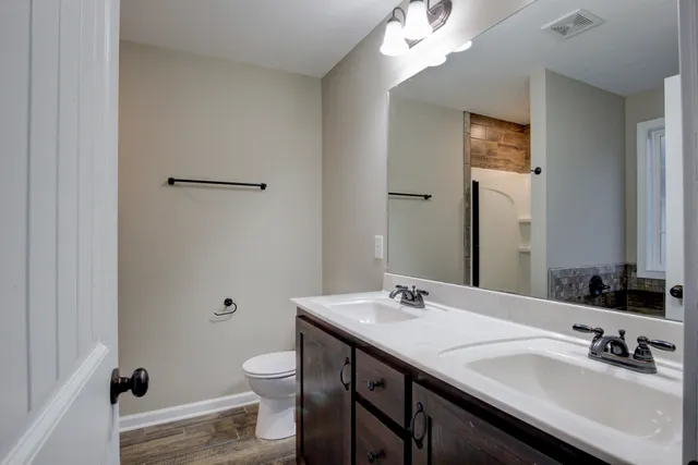 an empty room with wooden floor chandelier and windows