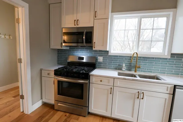 a kitchen with white cabinets appliances and sink