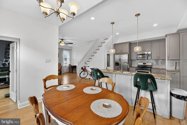 a kitchen with stainless steel appliances granite countertop a dining table chairs and stove top oven