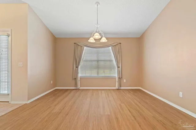 an empty room with wooden floor exposed radiator and windows
