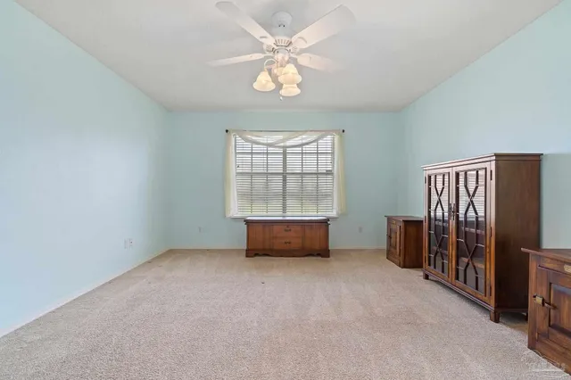 an empty room with windows and ceiling fan