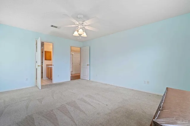 a view of an empty room with chandelier fan