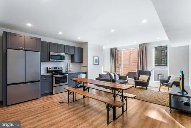 a living room with furniture and a kitchen area with wooden floor