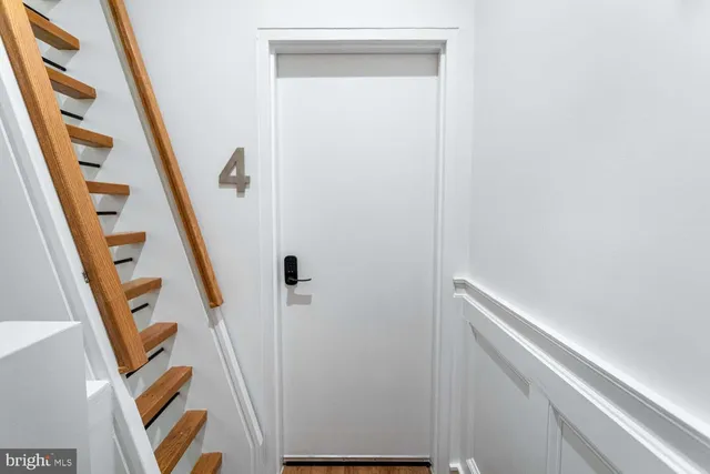 a view of a hallway with wooden floor and a white door