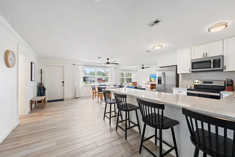 a kitchen with stainless steel appliances a dining table chairs and a refrigerator