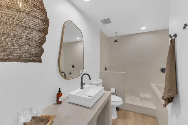 a bathroom with a sink a toilet and shower