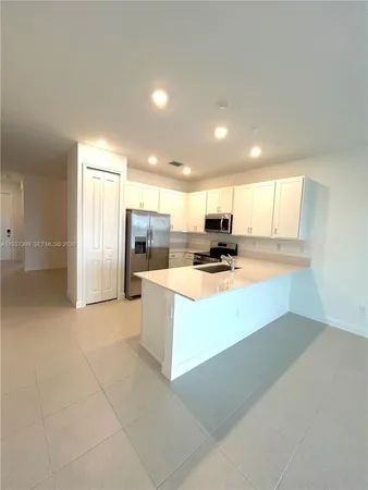 a large kitchen with kitchen island a stove a refrigerator a sink a dining table and chairs