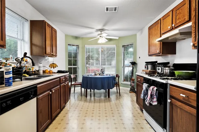 a kitchen with stainless steel appliances granite countertop a stove top oven a sink dishwasher a dining table and chairs with wooden floor