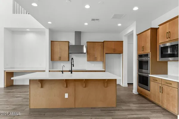 a view of kitchen with stainless steel appliances granite countertop a refrigerator a oven and a sink with wooden cabinets