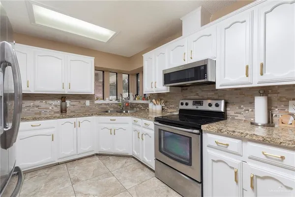 a kitchen with stainless steel appliances granite countertop a refrigerator sink and stove