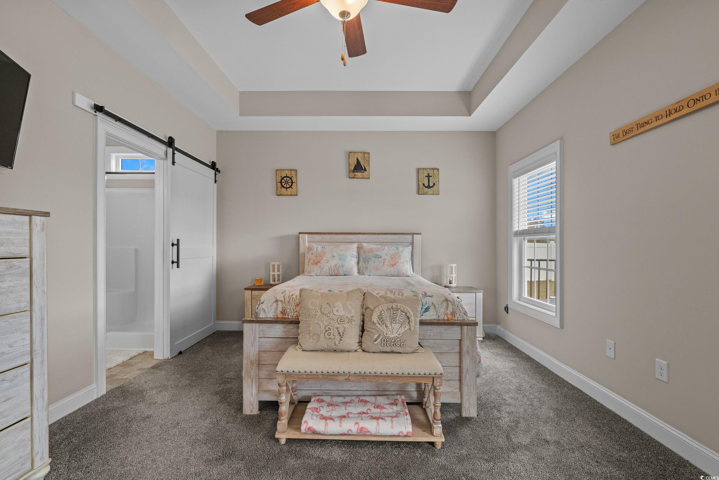 3624 Edwards Road Aynor, SC 29511 - Photo 21 of 40 Bedroom with a barn door, a tray ceiling, carpet, ensuite bath, and a ceiling fan