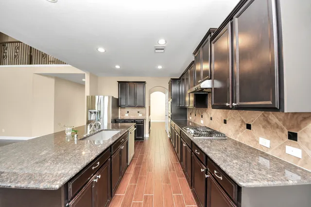 a kitchen with stainless steel appliances granite countertop a sink a stove and a refrigerator