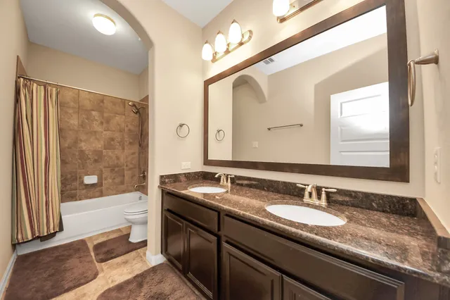 a bathroom with a granite countertop sink a mirror and a bathtub