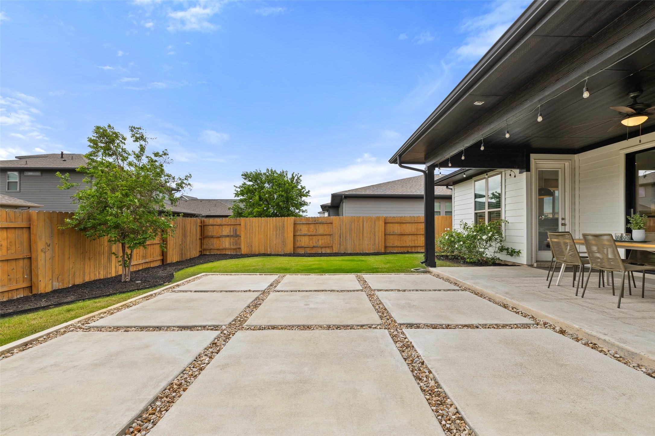 7908 Yokohama Terrace Austin, TX 78744 - Photo 40 of 40 a view of a patio with a table and chairs under an umbrella with plants and palm trees