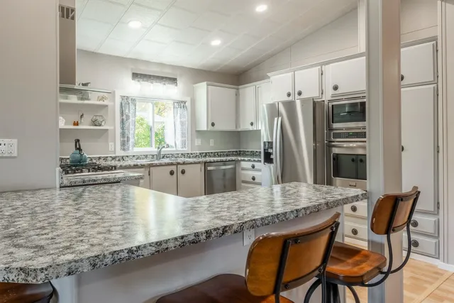 a kitchen with stainless steel appliances granite countertop a table chairs sink refrigerator and microwave