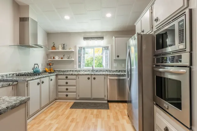 a kitchen with stainless steel appliances granite countertop a stove a sink and a refrigerator