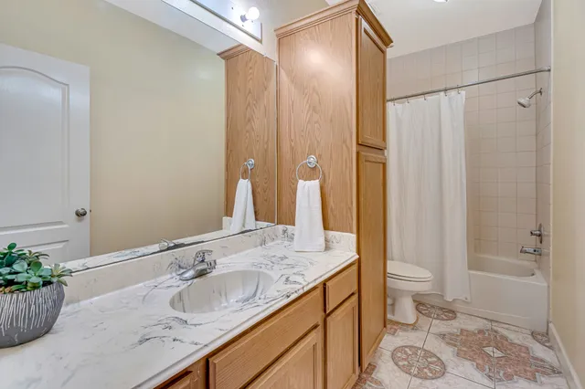 a bathroom with a granite countertop sink a toilet and shower