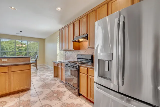 a kitchen with stainless steel appliances granite countertop a refrigerator and a stove