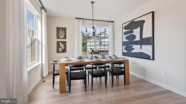 a kitchen with stainless steel appliances granite countertop a refrigerator a stove top oven a refrigerator a sink and a dining table with wooden floor