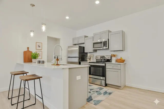 a kitchen with stainless steel appliances a stove a sink a microwave a refrigerator and cabinets