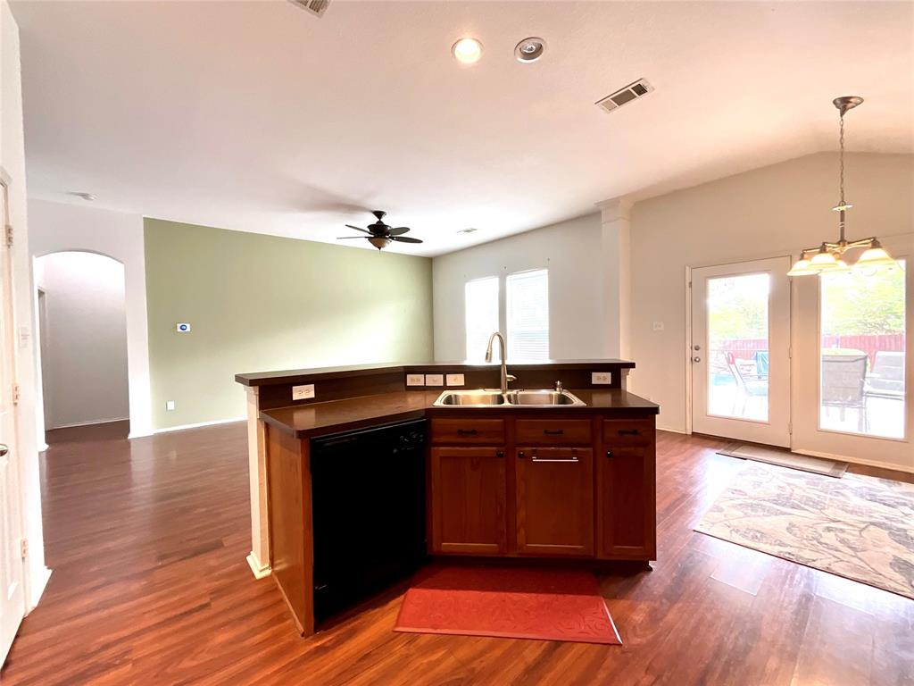 14044 Fontana Road Roanoke, TX 76262 - Photo 6 of 14 Kitchen island with integrated sink and dishwasher, wood-finish flooring, vaulted ceiling with chandelier, ceiling fan, and French doors providing exterior access