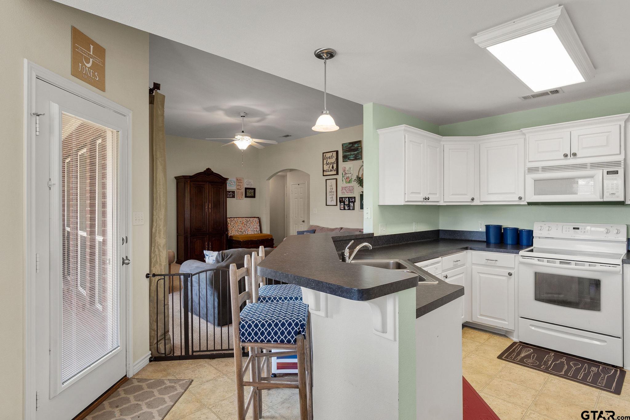 11269 Twin Spires Drive Flint, TX 75762 - Photo 8 of 23 a kitchen with a refrigerator a stove a sink dishwasher and white cabinets with wooden floor