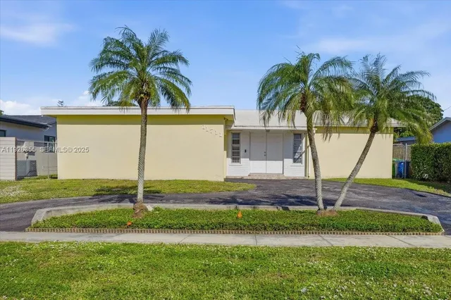 a palm tree sitting in front of a house with wooden fence
