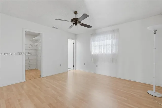 an empty room with wooden floor fan and windows