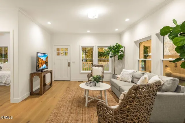 a living room with furniture and a dining table with wooden floor