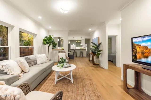 a living room with furniture kitchen view and a large window
