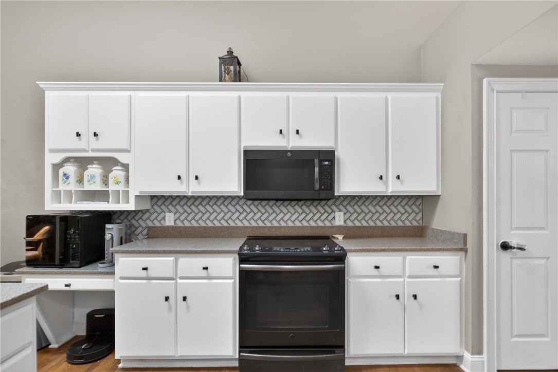 136 Loran Pointe Circle Seneca, SC 29672 - Photo 11 of 50 White cabinetry with black hardware frames the kitchen's functional layout, featuring ample countertop space and a stylish backsplash.