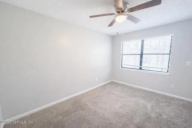 an empty room with windows and fan