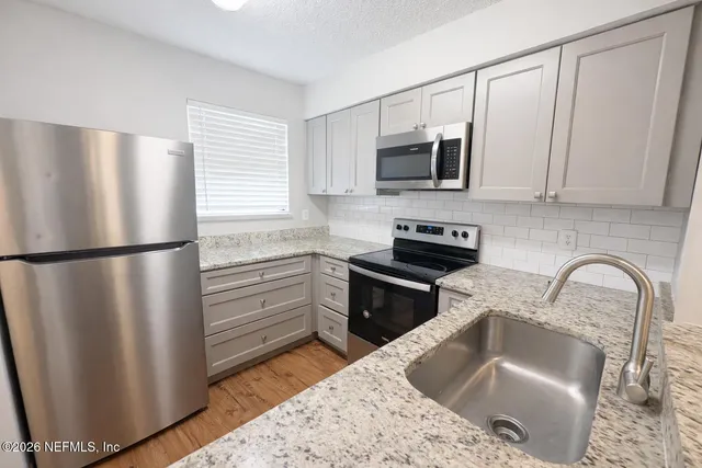 a kitchen with stainless steel appliances granite countertop a refrigerator sink and stove