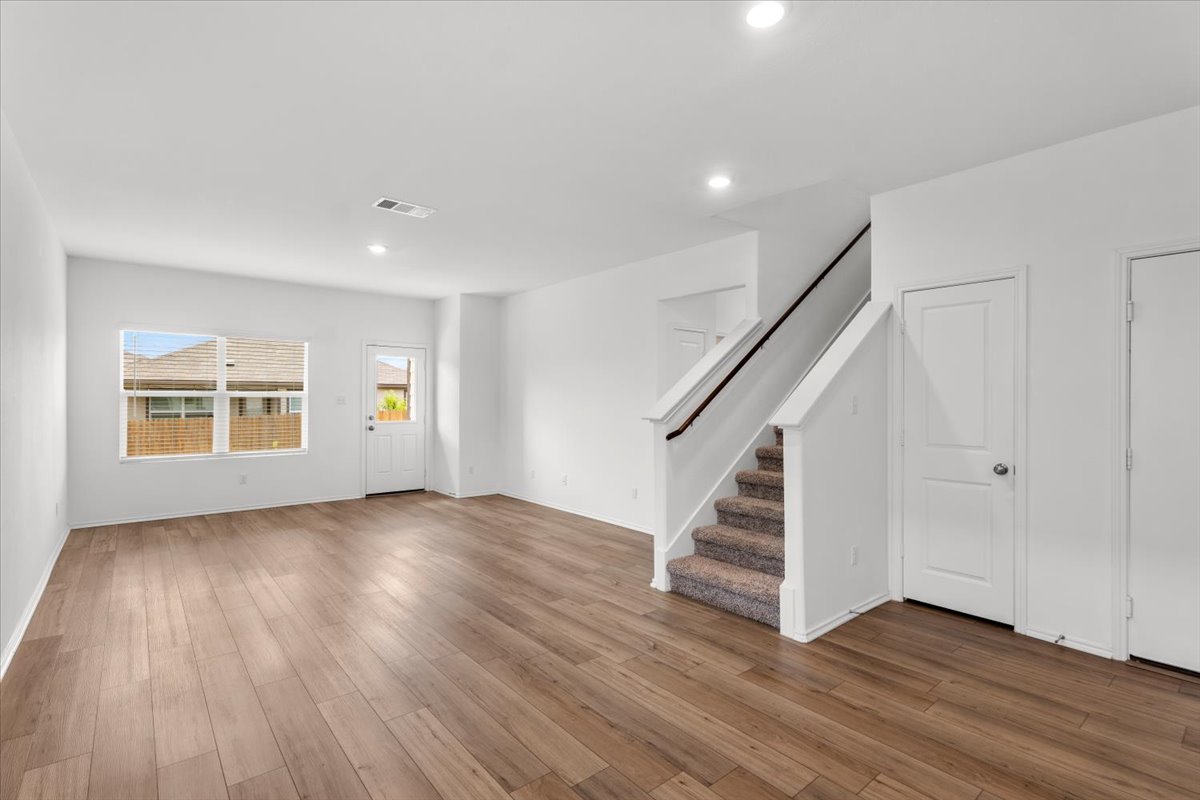 448 Perfect World Loop Jarrell, TX 76537 - Photo 12 of 40 A spacious living area features elegant hardwood flooring and a carpeted staircase leading to upper levels.