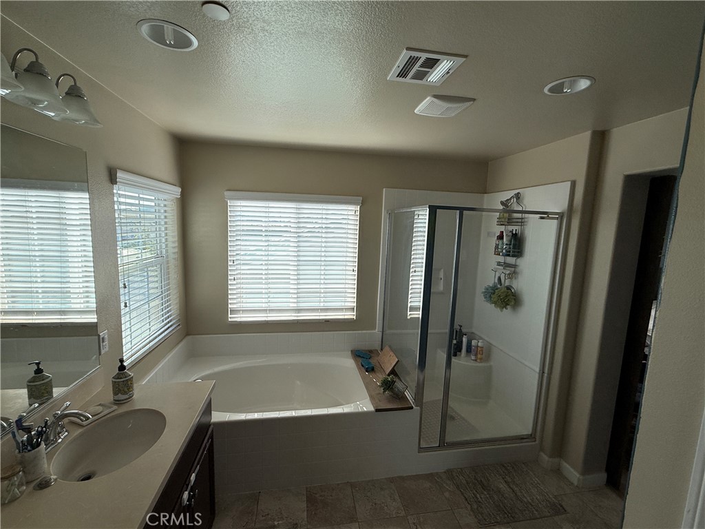 30130 Pine Needle Road Menifee, CA 92585 - Photo 29 of 45 a bathroom with a tub a sink a mirror and a shower