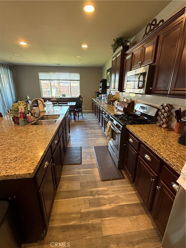30130 Pine Needle Road Menifee, CA 92585 - Photo 31 of 45 a kitchen with stainless steel appliances granite countertop sink stove and wooden floor