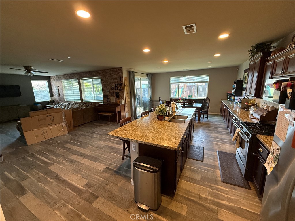 30130 Pine Needle Road Menifee, CA 92585 - Photo 34 of 45 a dining hall with stainless steel appliances granite countertop a stove a refrigerator a couch a dining table and chairs with the wooden floor